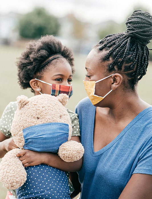 African American mom holding a young daughter with teddy bear