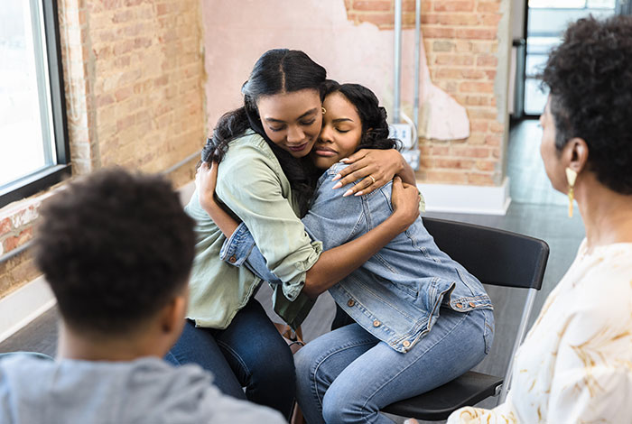 Two support group members hugging during therapy