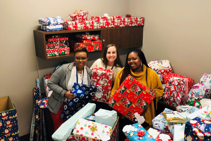 Centene employees pose with wrapped holiday gifts for donation