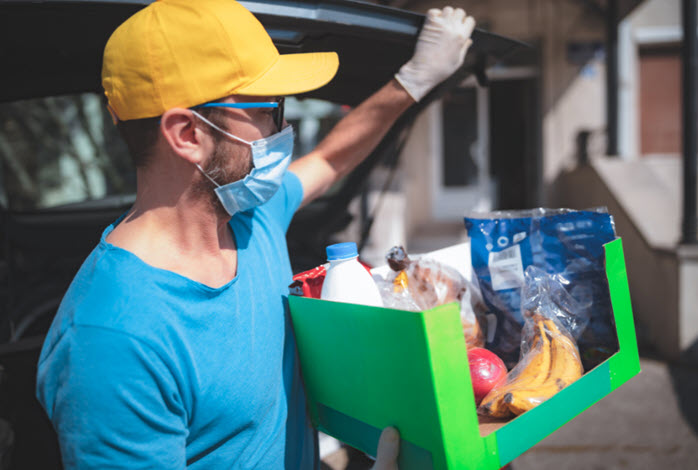 Volunteer in protective mask delivers food