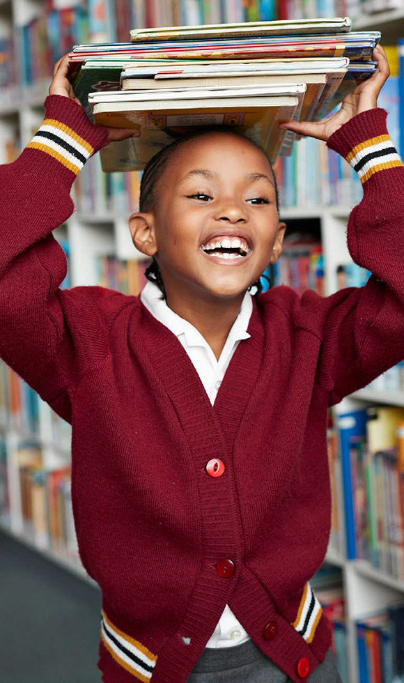 Child holding books on his head at library