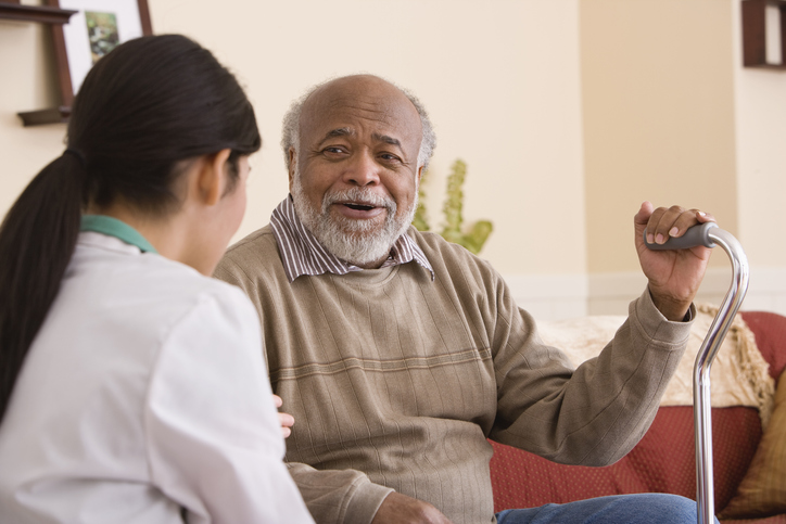 African American mature man with cane talking to nurse